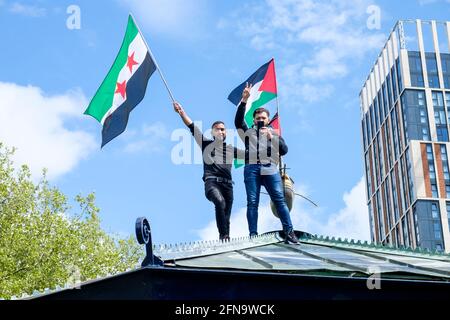 Bristol, Regno Unito. 15 maggio 2021. I sostenitori pro-palestinesi vengono raffigurati sventolando una bandiera in cima a uno stand di Castle Park mentre i sostenitori pro-palestinesi ascoltano i discorsi prima di una marcia di protesta pro-palestinese attraverso Bristol. La marcia di protesta e il rally si sono tenuti per consentire alle persone di mostrare il loro sostegno e la loro solidarietà con il popolo palestinese dopo 73 anni di Nakba e per protestare contro le recenti azioni di Israele a Gaza. Credit: Lynchpics/Alamy Live News Foto Stock