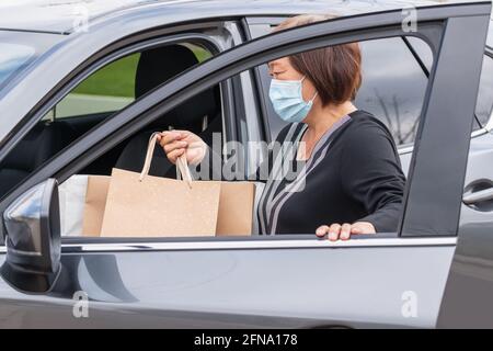 Donna asiatica matura con borsa per la spesa che entra nella sua auto Foto Stock