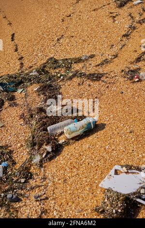 I rifiuti versati sulla spiaggia - bottiglie di plastica sporca usate vuote, confezioni e altri rifiuti domestici. Costa sabbiosa sporca. Inquinamento ambientale. Ecolog Foto Stock