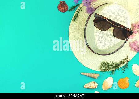 Vista dall'alto vacanza estiva con foglie tropicali e accessori femminili sulla spiaggia su uno sfondo luminoso, cappello di paglia, occhiali da sole e conchiglia Foto Stock