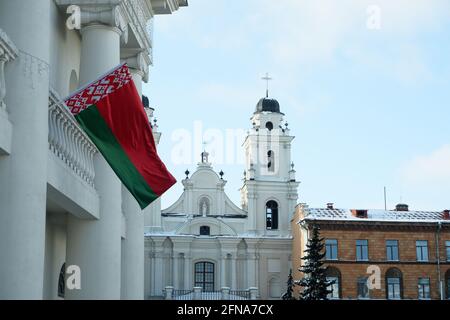 Minsk, Bielorussia - 6 febbraio 2021: Frammento di un antico edificio con colonne con una bandiera di stato bielorussa sventolante. Chiesa cattolica Foto Stock