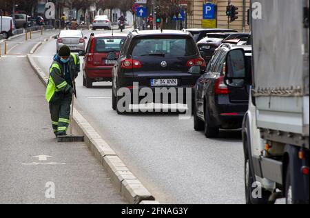 Bucarest, Romania - 15 aprile 2021: Una donna janitor travolta la spazzatura da una pista ciclabile a Bucarest. Foto Stock