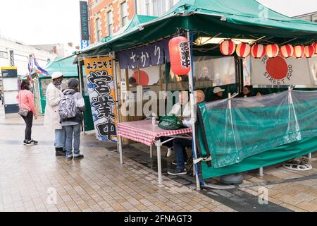 I clienti apprezzano il cibo di strada presso la stalla giapponese, il negozio da asporto aperto per affari nel mercato di Bromley, i clienti, gli acquirenti il sabato, Kent, Inghilterra Foto Stock