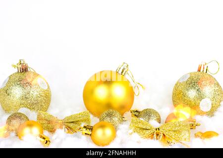 Decorazioni natalizie in oro brillante (nastri, baubles, archi, ornamenti) su fondo di neve artificiale bianca con spazio per la copia. Natale e Capodanno tradizionale Foto Stock