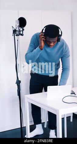 Uomo che indossa le cuffie davanti a un microfono - registrazione DI un brano. Foto di alta qualità Foto Stock