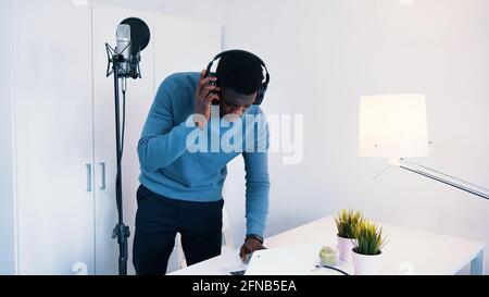 Uomo che indossa le cuffie che canta una canzone in un microfono in uno studio di registrazione. Foto di alta qualità Foto Stock