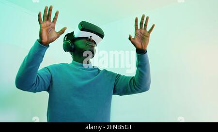 Uomo che indossa occhiali e cuffie VR e che gode di un ambiente virtuale a 360 gradi. Foto di alta qualità Foto Stock