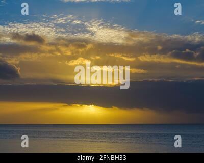 Il sole che tramonta sta per rompersi attraverso la copertura nuvolosa Foto Stock