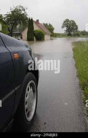 Überflutung auf der Landstrasse - Ein Auto steht an einer überschwemmten Straße Foto Stock