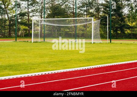 Pista da corsa con tapis roulant per atletica all'aperto dietro il cancello da calcio Foto Stock