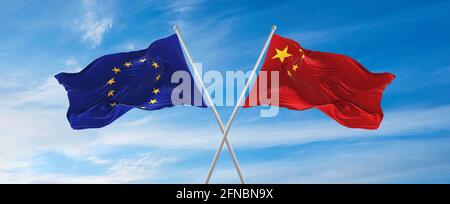 Bandiere dell'Unione europea e della cina che sventolano nel vento su pali di bandiera contro il cielo con le nuvole nella giornata di sole. Simboleggiando la relazione, dialogo tra due c Foto Stock