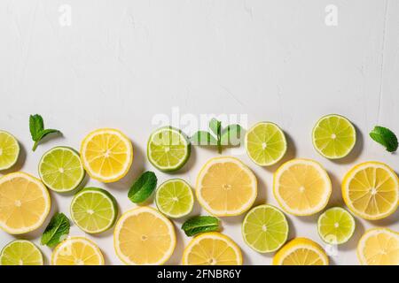 sfondo tropicale di agrumi. fette di limone, lime e foglie di menta Foto Stock