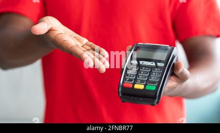 Vista ritagliata di un uomo nero in una macchina POS di tenuta uniforme Foto Stock