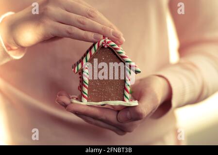 Una ragazza holdint pan di zenzero fatto in casa. Casa di pan di zenzero giocattolo. Tono в immagine Foto Stock