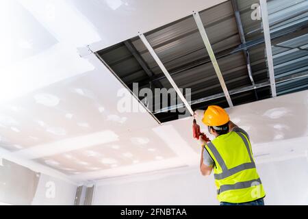 I lavoratori edili stanno installando la casa a soffitto nell'edificio in costruzione, idee di installazione a soffitto Foto Stock