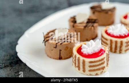 Set di mini pasticcini con diversi ripieni su un piatto, mettere a fuoco in primo piano Foto Stock