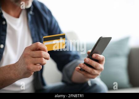 Uomo irriconoscibile con smartphone con carta di credito Foto Stock