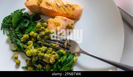 Salmone in camicia con piselli freschi e spinaci Foto Stock