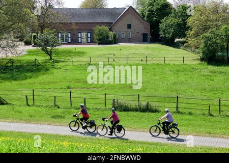 Rafahrer auf dem Rheindamm bei Rheinberg-Orsoy vor Industrie- und Naturkulisse. Foto Stock