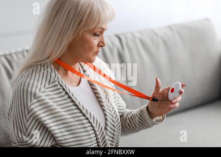 Sistema di chiamata di emergenza. Donna anziana che tiene premuto il pulsante di allarme Foto Stock