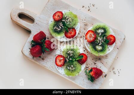 Panini con kiwi, fragole e semi di girasole sul tagliere. Colazione sana. Vista dall'alto, disposizione piatta Foto Stock