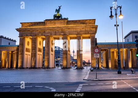 La porta di Brandeburgo con la torre della televisione all'alba, vista a Berlino, in Germania Foto Stock