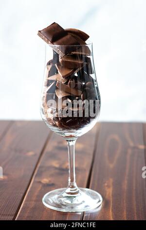 Bicchiere di vino riempito con diversi tipi di cioccolatini; dolce desiderio; spuntino al cioccolato Foto Stock