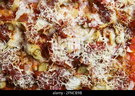 Vista dall'alto su una pizza preparata in casa, isolata e pronta a mangiare, con salsa di pomodoro, prosciutto di serrano, champignons, cipolle e crosta di formaggio pecorino croccante Foto Stock