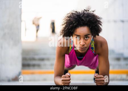 Donna afro atleta che fa pushup all'aperto. Foto Stock