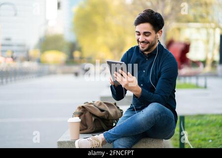 Giovane che ha una videochiamata su un tablet digitale all'aperto. Foto Stock