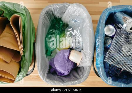 Un gruppo di vari tipi di rifiuti in sacchetti di plastica su tavolo di legno Foto Stock