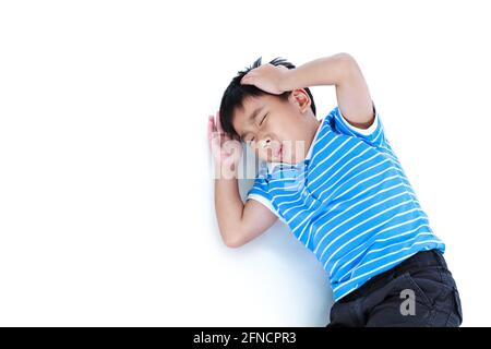 Vista dall'alto del bambino sdraiati. Il ragazzo asiatico ha un mal di testa, la mano sulla testa, segno di emozione. Isolato su sfondo bianco. Emozione umana negativa, faci Foto Stock