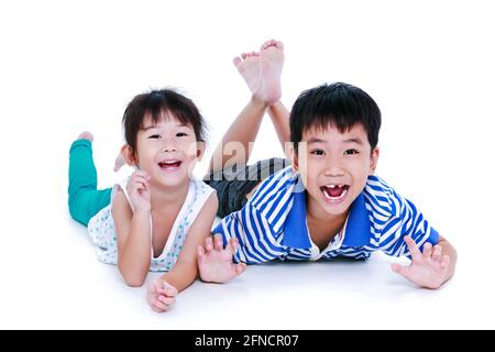 Bambini asiatici che si trovano inclini sul pavimento. Bambini cinesi felici e sorridenti, isolati su sfondo bianco. Concettuale circa l'amore del fratello. Happ Foto Stock