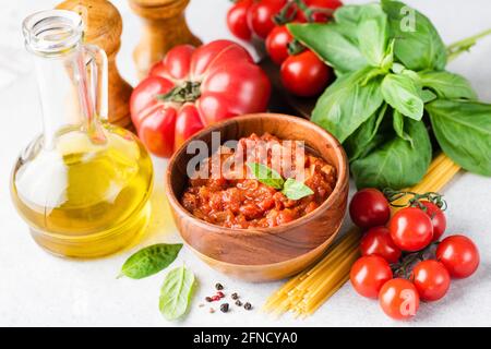 Salsa di pomodoro Marinara, olio d'oliva, pasta cruda, foglie di basilico verde e pomodori. Assortimento di ingredienti alimentari della cucina italiana Foto Stock