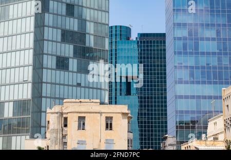 Parete di vetro dei grattacieli di Tel Aviv dietro un vecchio edificio in fase di ristrutturazione. Foto Stock