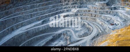 Ampio panorama di cava di pietra a cielo aperto con terrazze, escavatori e macchine frantumatrici di pietra Foto Stock