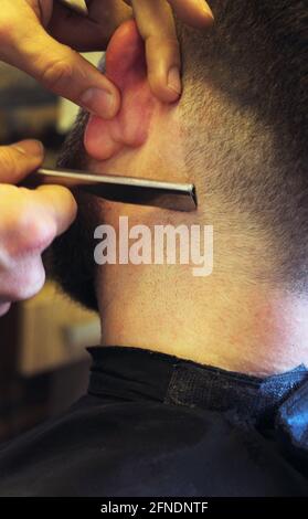 Un barbiere che dà un taglio di capelli al cliente maschile Foto Stock