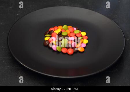 Caramelle colorate sulla piastra nera isolata su sfondo scuro Foto Stock
