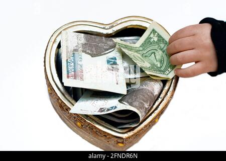 un bambino che mette 1 dollaro in una scatola di donazione con una forma del cuore, raccogliendo i soldi per la carità, aiutando la gente povera, una scatola con le valute multiple, donat Foto Stock