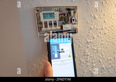 Collegamento di cavi codificati durante l'installazione di Google Nest Learning termostato durante un progetto di ristrutturazione intelligente della casa a Lafayette, California, 17 gennaio 2021. () Foto Stock