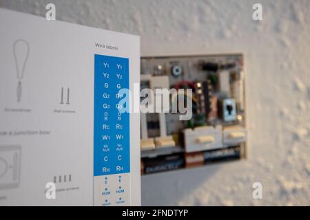 Collegamento di cavi codificati durante l'installazione di Google Nest Learning termostato durante un progetto di ristrutturazione intelligente della casa a Lafayette, California, 17 gennaio 2021. () Foto Stock