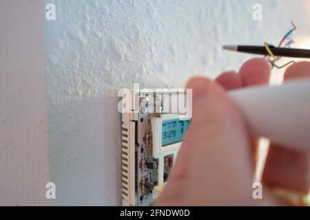 Collegamento di cavi codificati durante l'installazione di Google Nest Learning termostato durante un progetto di ristrutturazione intelligente della casa a Lafayette, California, 17 gennaio 2021. () Foto Stock