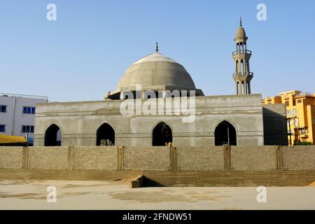 Una nuova moschea in costruzione contro il cielo azzurro soleggiato, costruendo una nuova moschea con la sua grande cupola in cemento Foto Stock