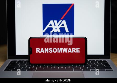 Logo AXA sullo sfondo sfocato e parola RANSOMWARE sullo smartphone di fronte. Stafford, Regno Unito, 16 maggio 2021. Foto Stock