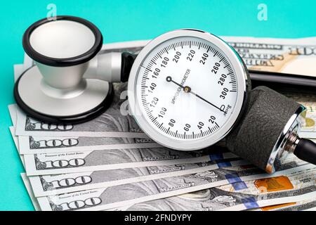 Stetoscopio, sfigmomanometro e denaro contante. Sanità, assicurazione sanitaria e concetto di bollette mediche. Foto Stock