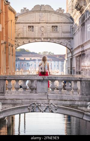 Giovane donna con gonna rossa, turista appoggiato su ringhiera ponte, ponte sul Rio di Palazzo, dietro Ponte dei Sospiri, Venezia, Veneto, Italia Foto Stock