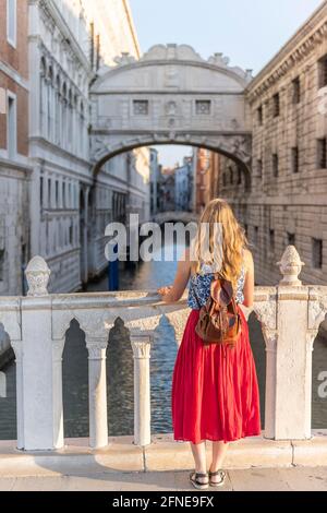 Giovane donna con gonna rossa, turista che guarda verso il Ponte dei Sospiri, Venezia, Veneto, Italia Foto Stock