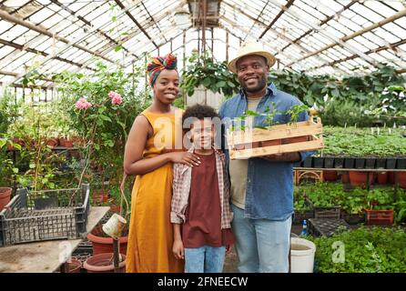 Ritratto della famiglia africana di tre sorridenti a macchina fotografica e. stnading nella serra Foto Stock