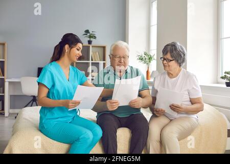 L'infermiere di assistenza domiciliare aiuta i pazienti anziani a capire e compilare contratto di assistenza homecare Foto Stock