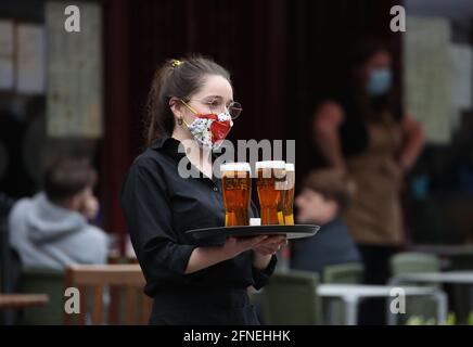 File foto datata 26/04/21 di un server che porta un vassoio di bevande da un pub nel Grassmarket di Edimburgo. I dirigenti dei pub e dei ristoranti hanno affermato che accogliere i clienti in migliaia di locali in tutto il paese aiuterà il settore a 'tornare sulla strada della normalità'. Data di emissione: Lunedì 17 maggio 2021. Foto Stock